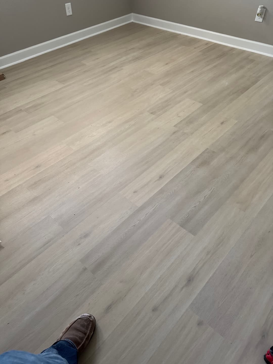 Light wooden floor with a person's foot in a room, showcasing a modern interior design.