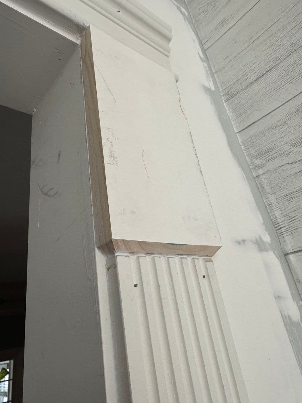 Interior door frame with detailed molding and unfinished wood corner trim.