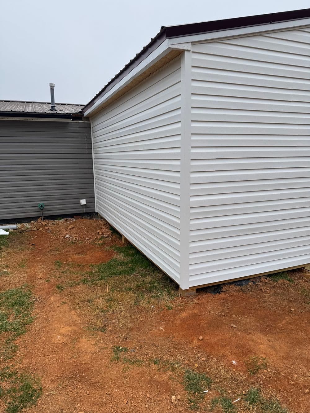 Side view of a newly installed white vinyl siding on a residential building.